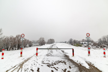 Naklejka premium Novi Sad, Serbia - January 23, 2019: Danube island (Šodroš) near Novi Sad, Serbia. Colorful landscape with snowy trees, road covered with snow, beautiful frozen river and barrier.