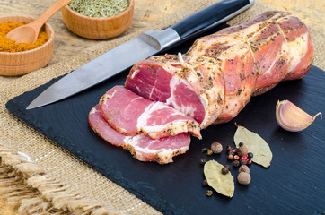 Traditional smoked pork neck with herbs and spices on wooden table