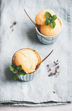 Fresh homemade grapefruit sorbet ice cream scoops in ceramic cups over linen napkin. Healthy vegan summer dessert