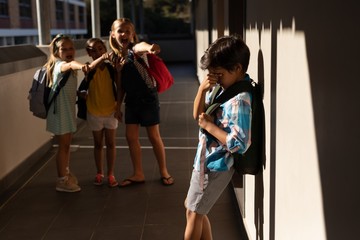 Obraz na płótnie Canvas School friends bullying a crying boy in hallway of elementary