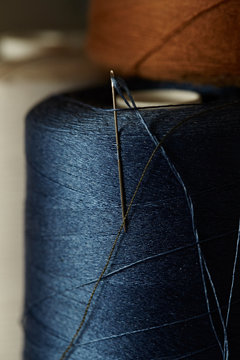 closeup of spool of blue thread with needle
