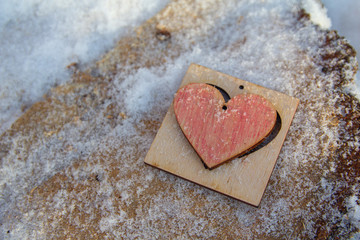 Wooden heart behind a snow-covered surface. Valentine's Day