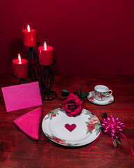 Floral pattern china dinnerware with matching plate, cup and saucer. pink rose, pink napkin, silverware, red candles and pink card