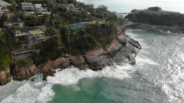 Top down aerial view of the ocean the cliff rocks of Joatinga beach in Rio de Janeiro revealing the wider surrounding with in the background the Two Brothers mountain