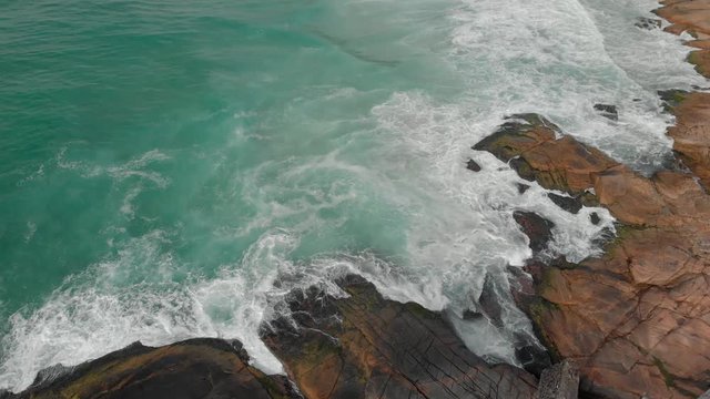 Panning up from the rocks at Joatinga beach revealing the ocean waves rolling in in Rio de Janeiro