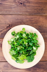 Mix of corn salad and spinach leaves on wooden plate