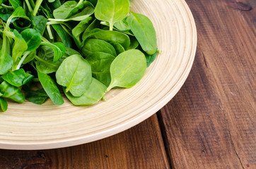 Mix of corn salad and spinach leaves on wooden plate