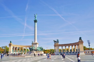 Millennium Monument on the Heroes' Square Hosok Tere under picturesque sky at sunny summer day. Blurred unrecognizable faces of people. One of the most visited attractions squares in Budapest, Hungary