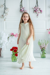 Portrait of a beautiful blue-eyed child, a little girl with a bouquet of tulips in a bright room.