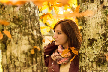 Portrait of a young woman with reddish hair among the trunks of an autumnal forest