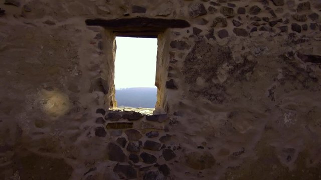 Bright afternoon view of the Romanian countryside and a small village.  Pull back through an opening in an old rock wall of a medieval fortress.