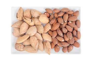 Dried peeled and unpeeled whole almonds on white plate