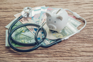 Financial health check or EU economic concept, saving white piggy bank with stethoscope on pile of...