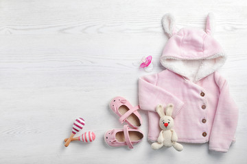 Flat lay composition with cute clothes and space for text on white wooden background. Baby accessories