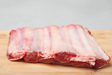Board with raw ribs on grey background, closeup. Fresh meat