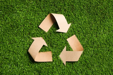 Poster Recycling symbol cut out of kraft paper on green grass, top view © New Africa