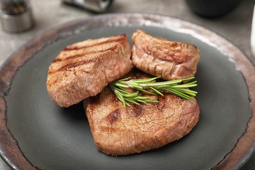 Grilled meat with rosemary on plate, closeup