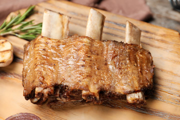 Roasted ribs on wooden board, closeup. Tasty meat