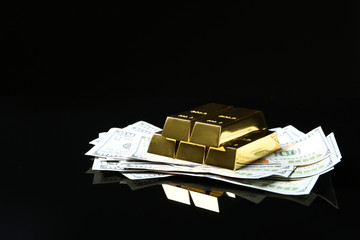 Shiny gold bars and money on black background