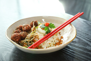 Plate with rice, meat balls and chopsticks served on table