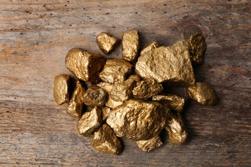 Pile of gold nuggets on wooden background, top view