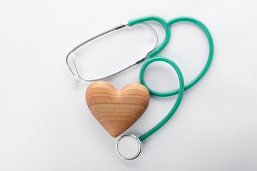 Stethoscope with wooden heart on white background, top view