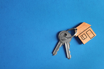 House keys with trinket on color background, top view. Space for text