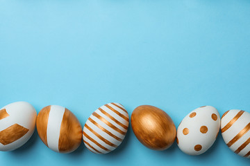 Set of traditional Easter eggs decorated with golden paint on color background, top view. Space for text