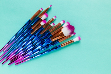  Set of various professional trendy fashion violet purple metallic makeup brushes on pastel green background. Flat lay, top view. Accessories for make up, fashion background,  