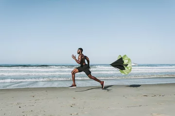 Tuinposter Fit man with a running parachute at the beach © Rawpixel.com
