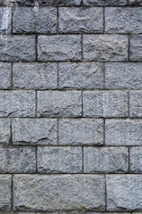 Wall of large granite rough gray stone blocks. Background. Texture. Vertical frame