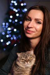 Portrait of young woman with can on hands and Christmas tree background 