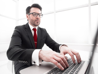 close up.serious businessman typing on a laptop