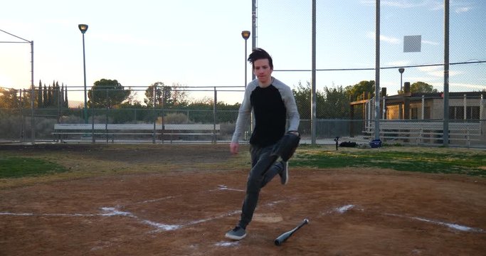 A baseball player bunts a pitch at home plate with his bat running to first base as the catcher grabs the ball during a park game at sunset.