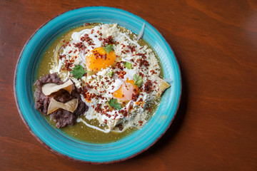 Bright plate with delicious breakfast of huevos verdes, or eggs in verde salsa in Mexico
