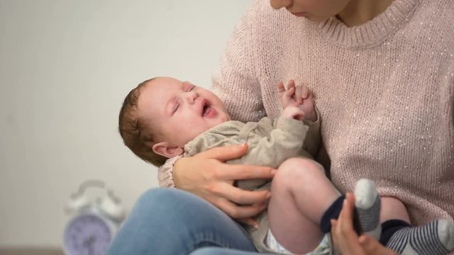 Young mom feeding little baby son from bottle, infant formula artificial feeding