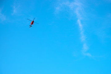 Fototapeta na wymiar Red helicopter in blue sky. Emergency service helicopter flight. Red helicopter banner template with text place.