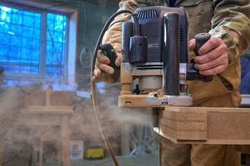 Carpenter working with manual hand milling machine in the workshop. Wooden furniture manufacturing...