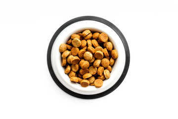 Dry dog food in bowl on white backgorund top view copy space