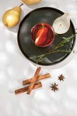Obraz na płótnie Canvas Delicious spicy hot mulled red wine with cinnamon, star anise and slice pear served in a carafe and glass for a cold winter evening or festive Christmas beverage