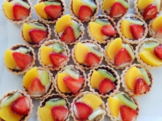 Top view of mini tarts with fresh strawberries, orange and kiwi isolated on white background 