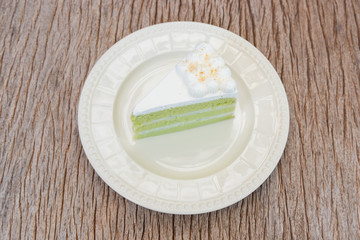 soft green coconut cream cake in a piece on clean plate, put on the bark wooden texture table