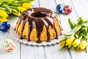 Delicious holiday slovak and czech cake babovka with chocolate glaze. Easter decorations - spring tulips and eggs