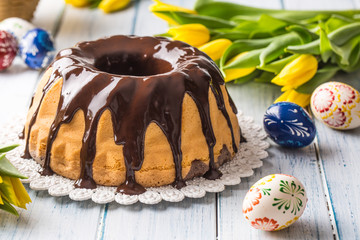 Delicious holiday slovak and czech cake babovka with chocolate glaze. Easter decorations - spring tulips and eggs
