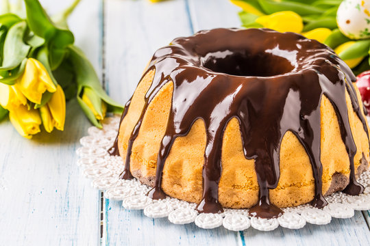 Delicious holiday slovak and czech cake babovka with chocolate glaze. Easter decorations - spring tulips and eggs