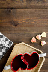 Fototapeta na wymiar Valentine's day concept. Heart-shaped mugs and sweets on dark wooden background top view space for text