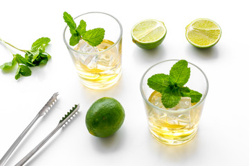 Copmosition with whiskey. Iced whiskey near mint, lime, bar tongs on white background top view