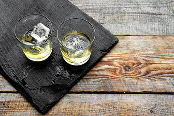 In the bar. Whiskey with ice on black desk on wooden background top view copy space