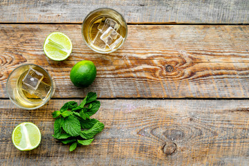 Alcoholic beverage. Whiskey with ice, mint and lime on dark wooden background top view copy space