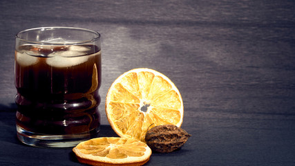 Drink with ice in a stanie on a dark background and oranges.